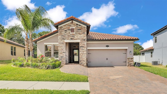 mediterranean / spanish house featuring a tile roof, decorative driveway, central AC, an attached garage, and stone siding