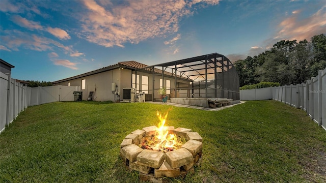 view of yard with a fenced backyard, glass enclosure, an outdoor fire pit, and a patio area