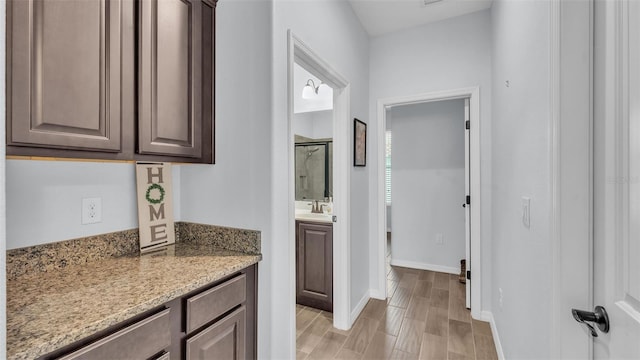 full bath featuring vanity, baseboards, a shower with door, and wood finished floors