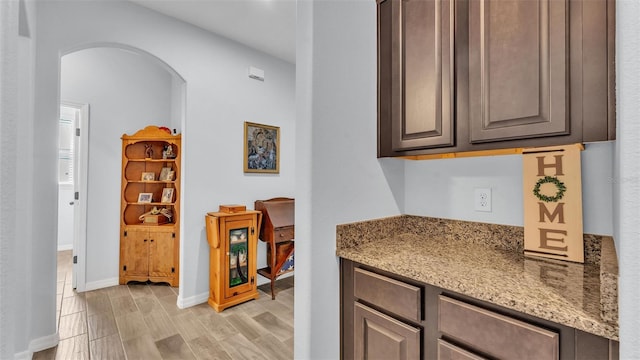 interior space with arched walkways, baseboards, and light wood-style floors
