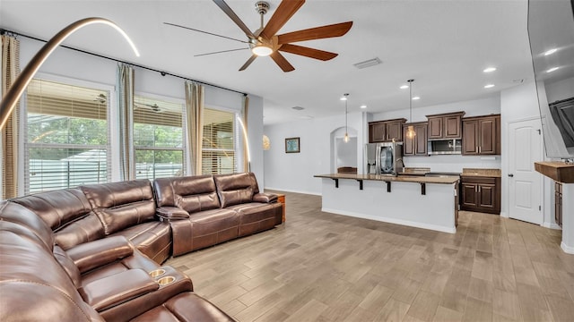 living room featuring ceiling fan, visible vents, baseboards, light wood-style floors, and recessed lighting
