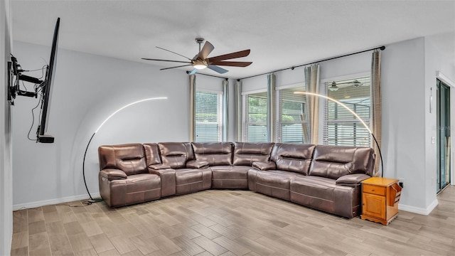 living area with baseboards, ceiling fan, and light wood finished floors