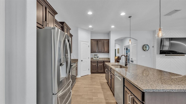 kitchen with visible vents, appliances with stainless steel finishes, arched walkways, a sink, and light wood-style floors