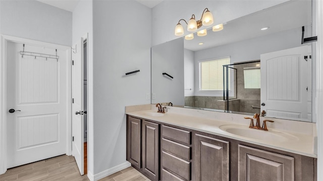 bathroom featuring double vanity, tiled shower, a sink, and wood finished floors