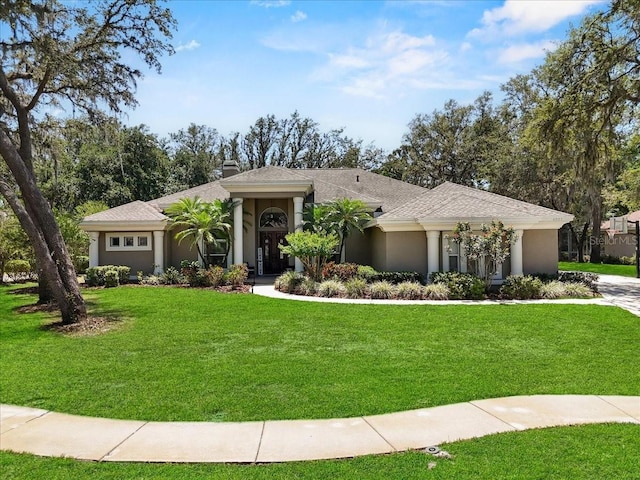 view of front of home featuring a chimney, a front lawn, and stucco siding