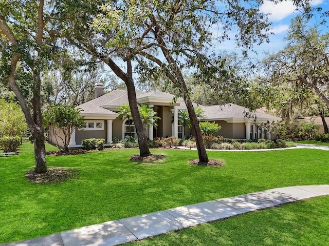 ranch-style house with a front yard, stucco siding, and a chimney