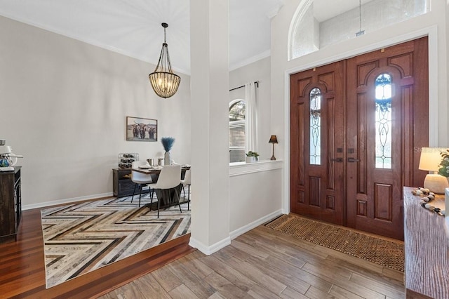 entryway featuring baseboards, a chandelier, a wealth of natural light, and ornamental molding