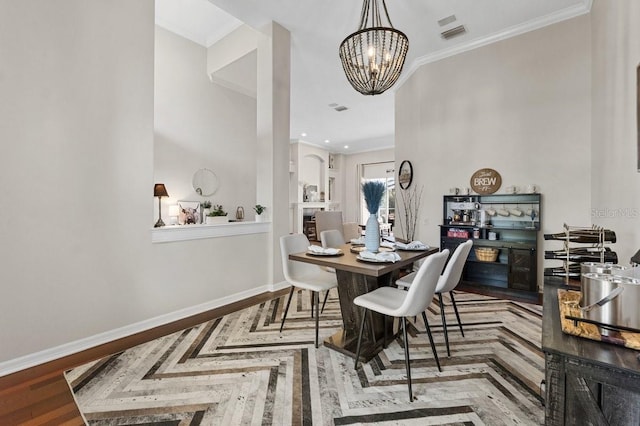 dining room with crown molding, a notable chandelier, wood finished floors, and baseboards