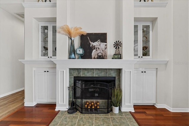 details featuring baseboards, wood finished floors, and a tiled fireplace
