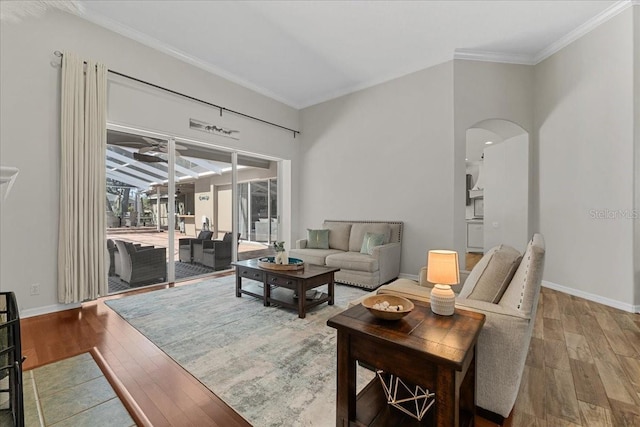 living room featuring hardwood / wood-style floors, baseboards, arched walkways, and crown molding