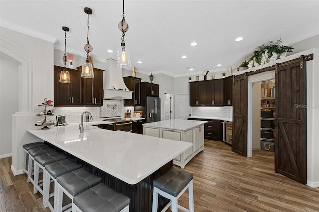 kitchen featuring appliances with stainless steel finishes, a kitchen bar, decorative backsplash, and premium range hood