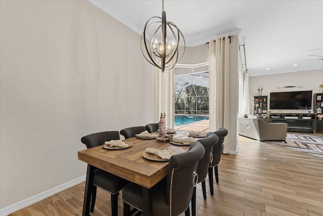 dining area featuring baseboards, wood finished floors, a notable chandelier, and ornamental molding