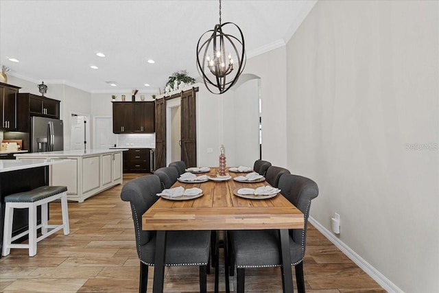 dining area with light wood finished floors, recessed lighting, ornamental molding, and arched walkways