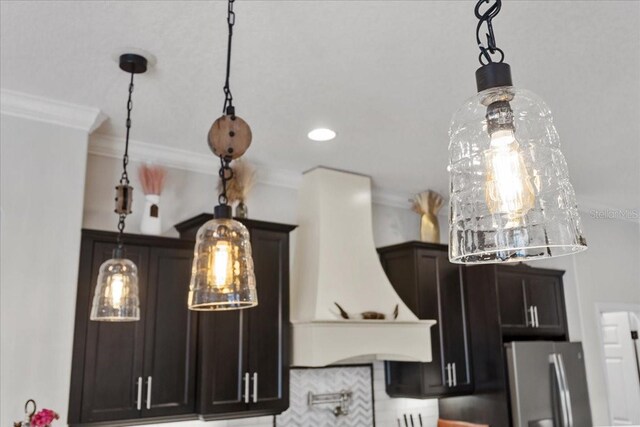 details featuring crown molding, premium range hood, freestanding refrigerator, and hanging light fixtures