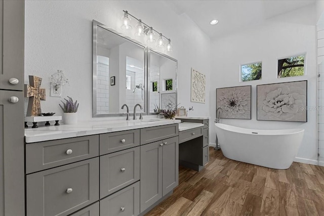 bathroom with a soaking tub, wood finished floors, an enclosed shower, and vanity