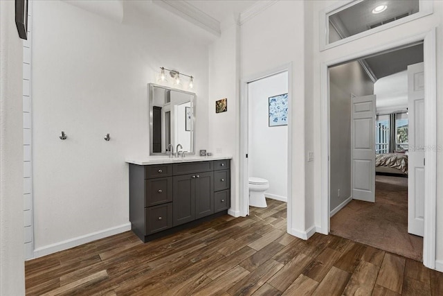 ensuite bathroom with toilet, baseboards, ornamental molding, wood finished floors, and ensuite bathroom