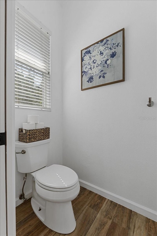 bathroom with toilet, wood finished floors, and baseboards