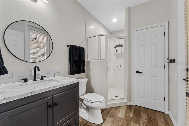 bathroom featuring a stall shower, toilet, wood finished floors, and vanity