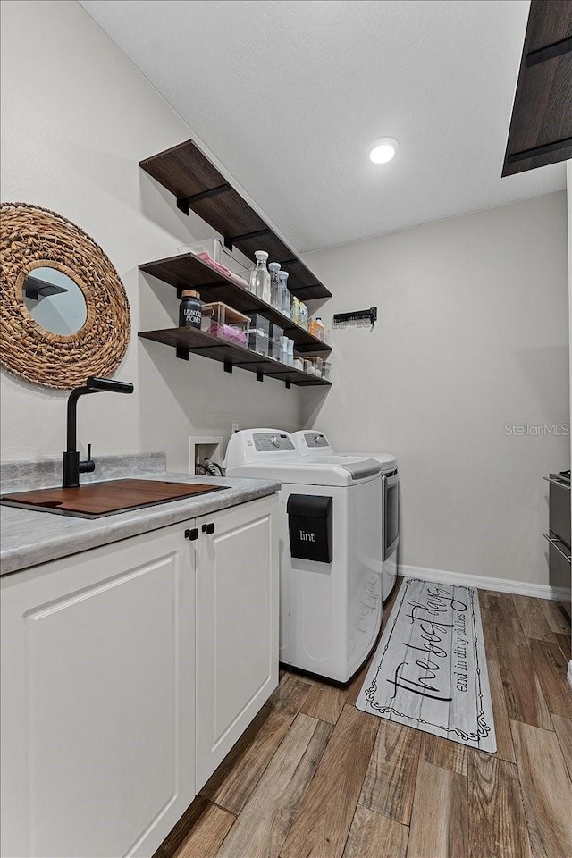 washroom featuring baseboards, wood finished floors, cabinet space, and separate washer and dryer