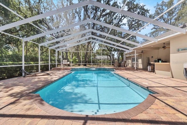 view of swimming pool with ceiling fan, a patio, glass enclosure, and a pool with connected hot tub