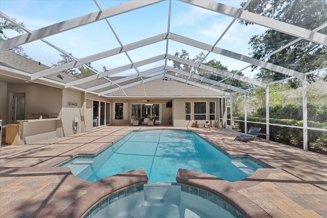 view of swimming pool with a ceiling fan, a patio, glass enclosure, and a pool with connected hot tub