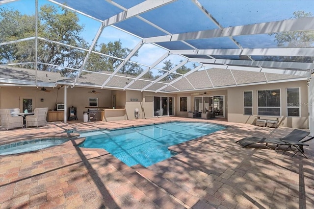 view of swimming pool with a patio, ceiling fan, glass enclosure, and a pool with connected hot tub