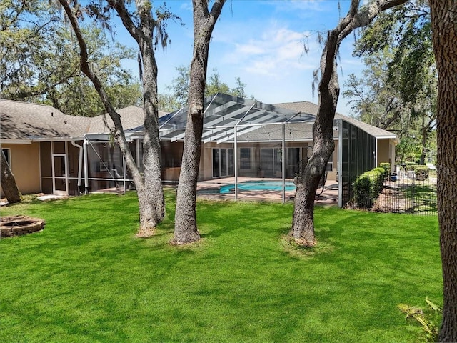 rear view of property with a fire pit, an outdoor pool, a shingled roof, a lawn, and fence