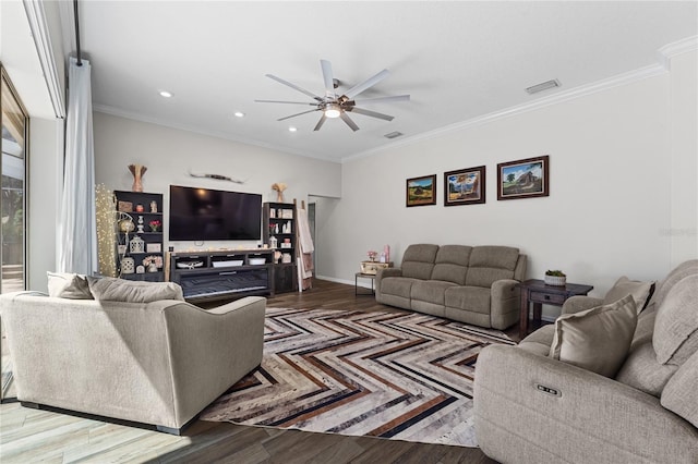 living area featuring ceiling fan, visible vents, baseboards, ornamental molding, and wood finished floors