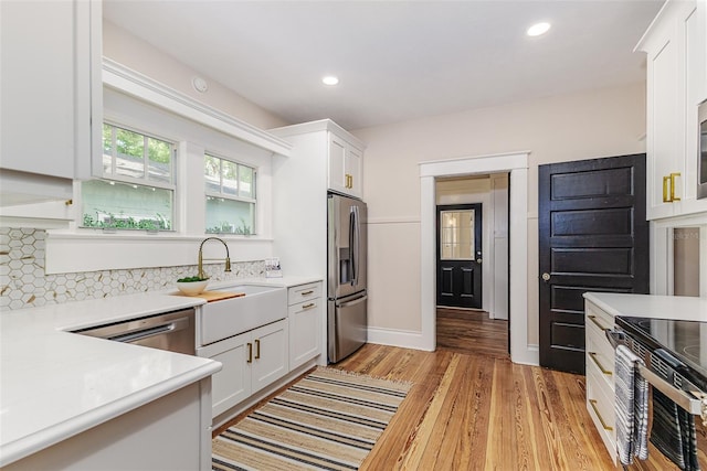 746 Mississippi Ave, Lakeland, FL 33801 - kitchen with appliances with stainless steel finishes, light wood-style flooring, light countertops, and white cabinets