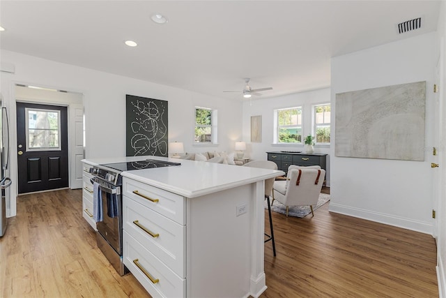 746 Mississippi Ave, Lakeland, FL 33801 - kitchen with stainless steel appliances, a kitchen breakfast bar, a center island, light wood-style flooring, and white cabinets