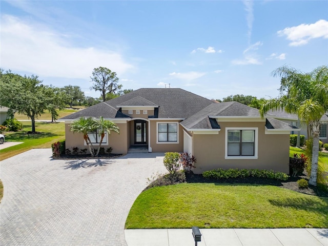1295 Osprey Landing Dr, Lakeland, FL 33813 - prairie-style house featuring a front yard, stucco siding, decorative driveway, and roof with shingles