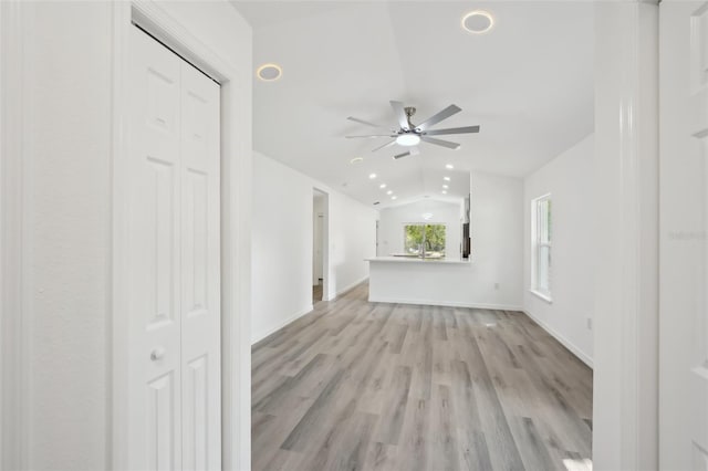 unfurnished living room with ceiling fan, light wood-style floors, recessed lighting, baseboards, and vaulted ceiling