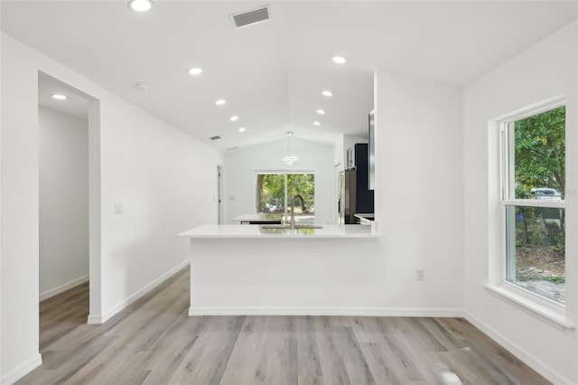 kitchen with visible vents, vaulted ceiling, light wood-type flooring, a sink, and light countertops
