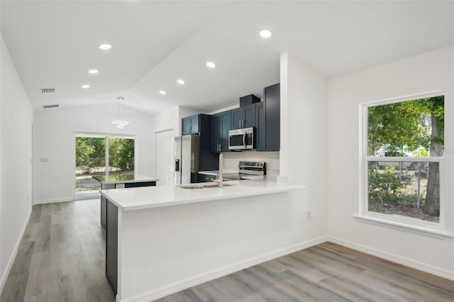 kitchen with light countertops, light wood-style floors, stainless steel appliances, and vaulted ceiling