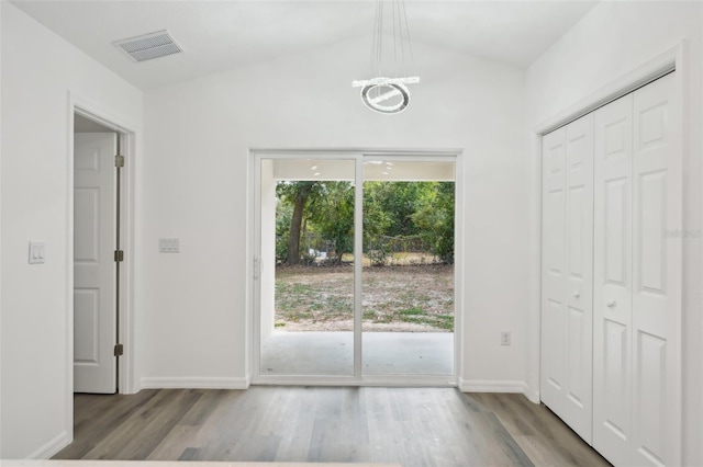 doorway with baseboards, vaulted ceiling, wood finished floors, and visible vents