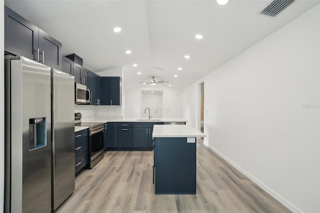 kitchen featuring lofted ceiling, light countertops, a sink, light wood finished floors, and stainless steel appliances