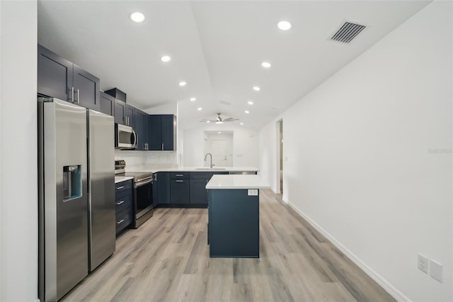 kitchen featuring vaulted ceiling, a sink, light countertops, a peninsula, and stainless steel appliances