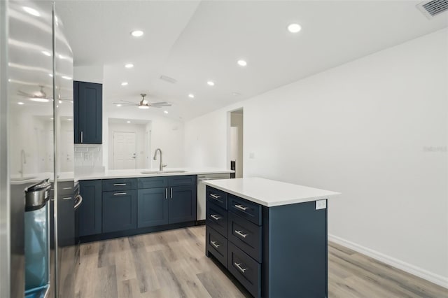 kitchen with visible vents, a peninsula, light wood-style floors, a sink, and vaulted ceiling