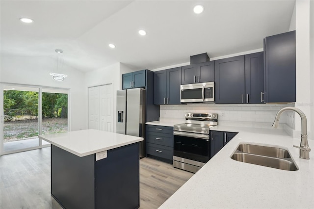 kitchen featuring a sink, light wood finished floors, appliances with stainless steel finishes, backsplash, and vaulted ceiling