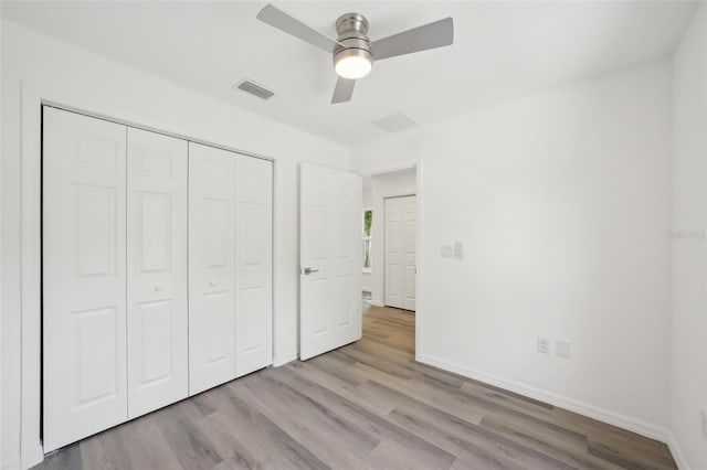 unfurnished bedroom with baseboards, a closet, wood finished floors, and visible vents