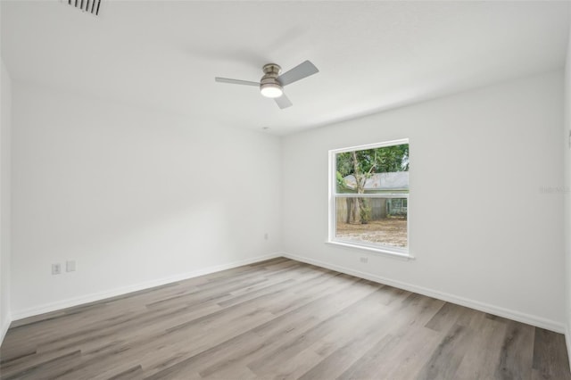 unfurnished room featuring baseboards, ceiling fan, wood finished floors, and visible vents