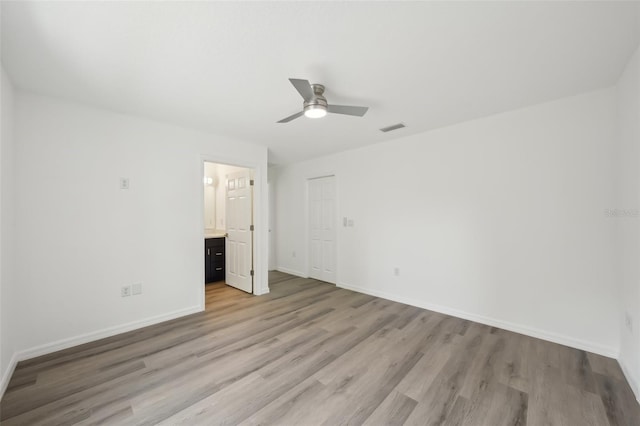 unfurnished bedroom featuring ceiling fan, visible vents, light wood-type flooring, baseboards, and ensuite bathroom