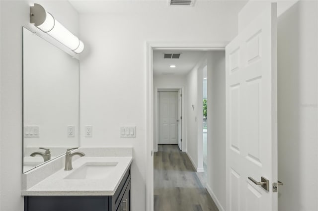 bathroom featuring vanity, baseboards, wood finished floors, and visible vents