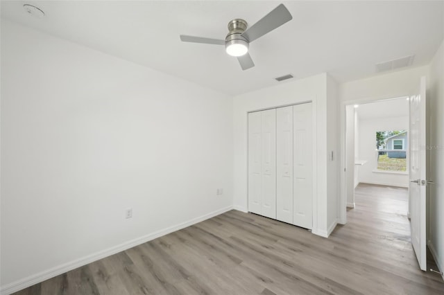 unfurnished bedroom with baseboards, a closet, wood finished floors, and visible vents