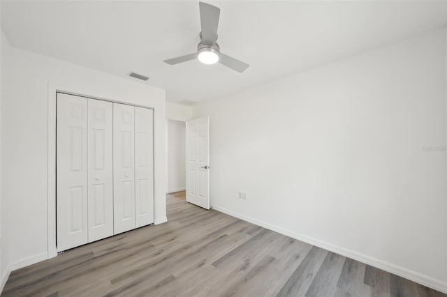 unfurnished bedroom with baseboards, visible vents, wood finished floors, and a closet