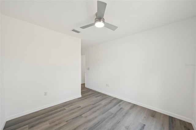 spare room featuring a ceiling fan, baseboards, visible vents, and wood finished floors