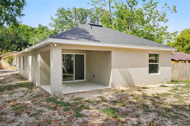 back of property with a patio area, stucco siding, fence, and roof with shingles