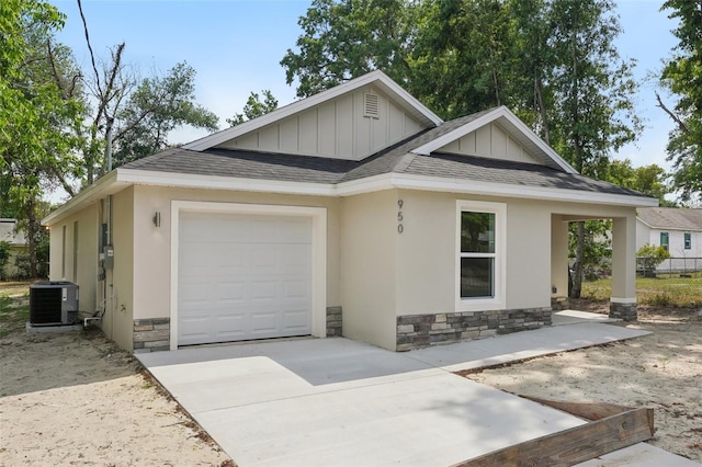 view of front facade with a garage, stone siding, cooling unit, a shingled roof, and board and batten siding