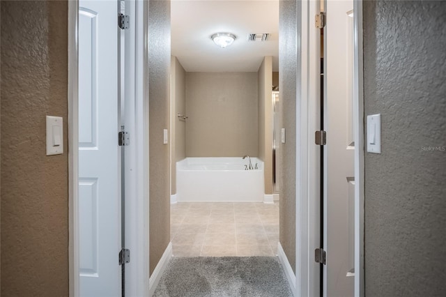 2933 Blackwater Oaks Dr, Mulberry, FL 33860 - hallway featuring a textured wall, visible vents, carpet floors, baseboards, and tile patterned floors
