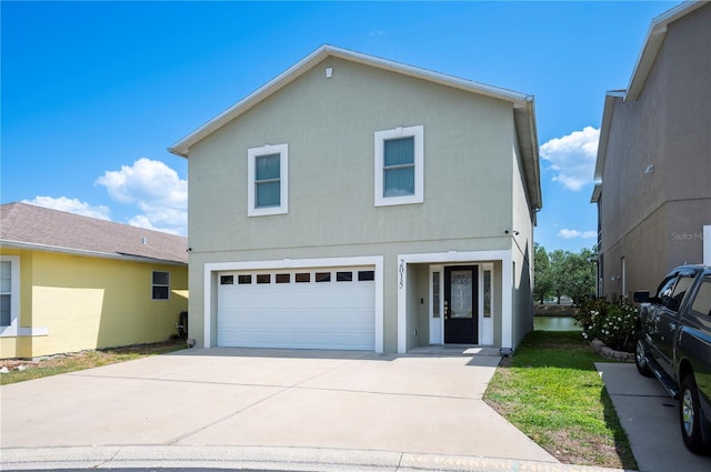 traditional home with an attached garage, driveway, and stucco siding